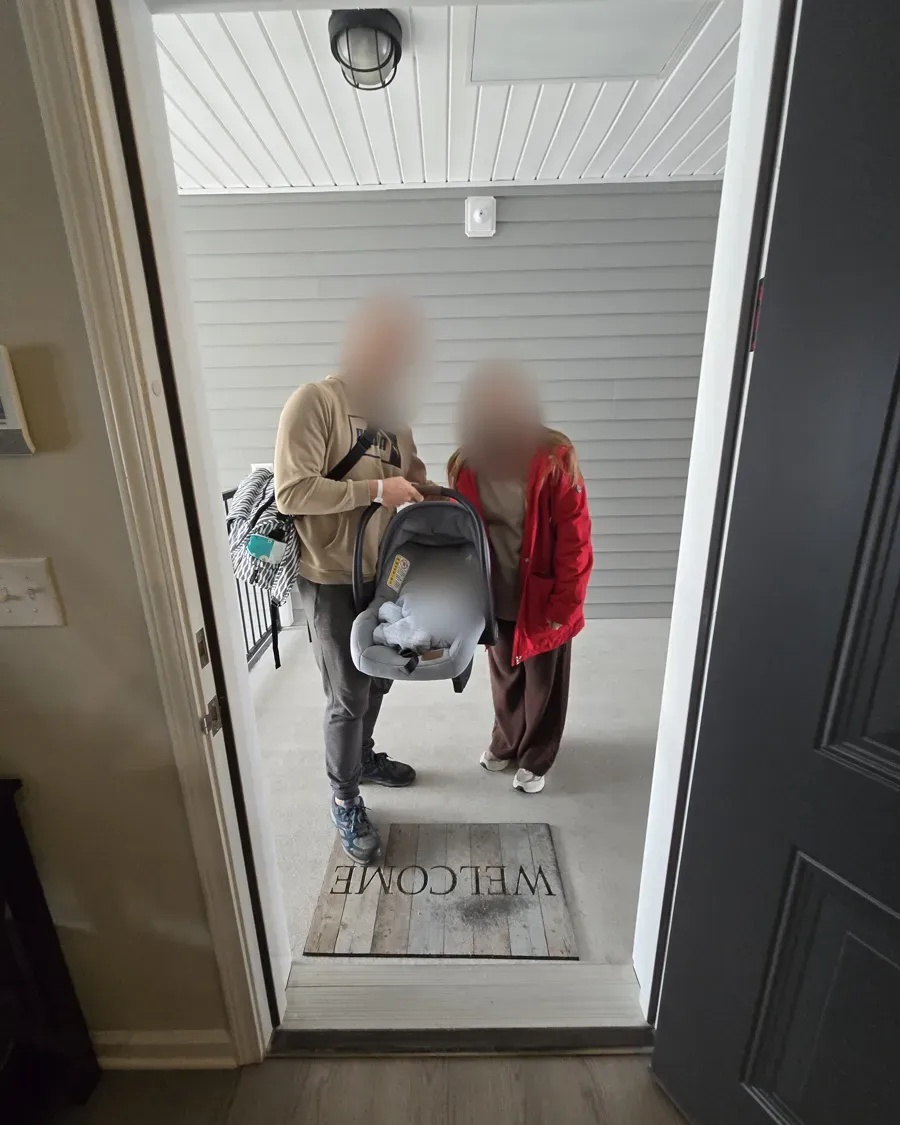 Unos padres llegan a casa con su bebé recién nacido en la sillita